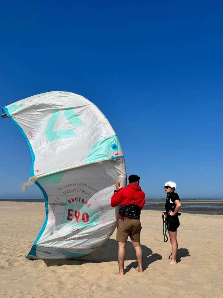 Femme apprenant le maniement d’une aile de kitesurf sur la plage en Zélande