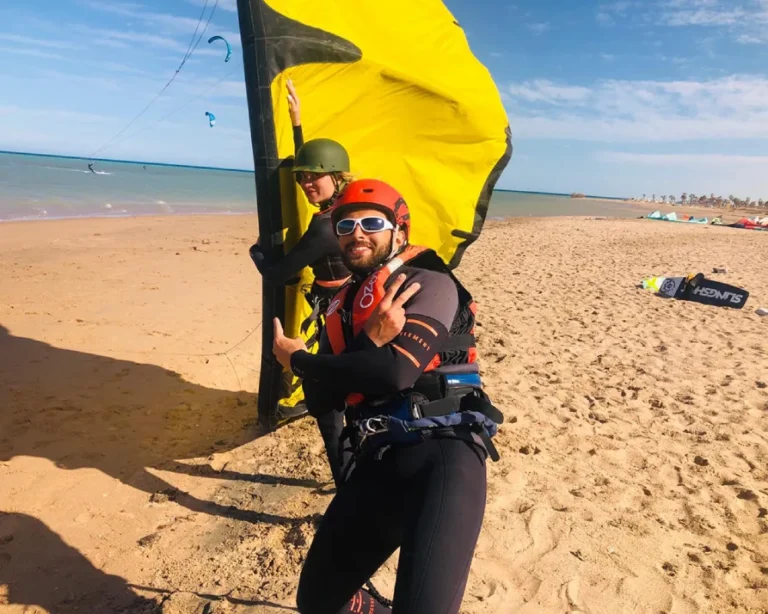 Een KiteTrek-instructeur begeleidt een volledig uitgeruste cursist vóór zijn eerste kitesurfsessie in Zeeland.